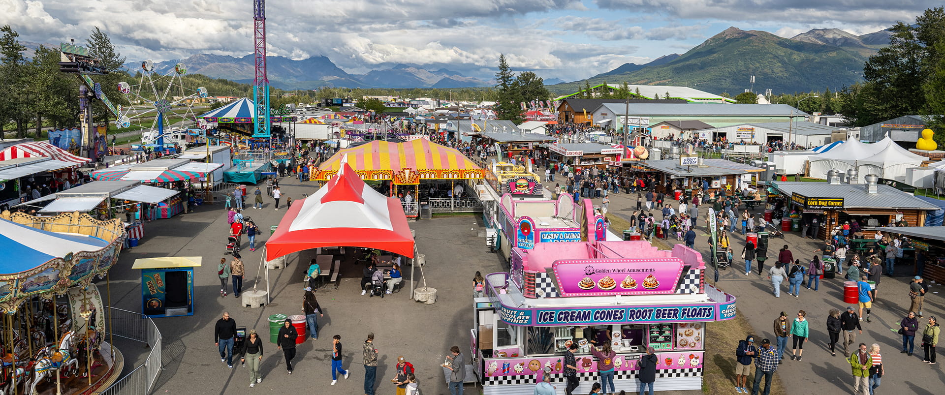 A bustling fairground filled with colorful tents, rides, and crowds of people enjoying the festivities in Mat-Su, Alaska