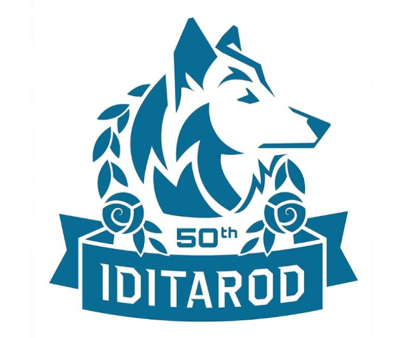 A stylized blue wolf head with a fiery mane, surrounded by laurel leaves and roses, commemorating the 50th anniversary of IDITAROD in Mat-Su, Alaska
