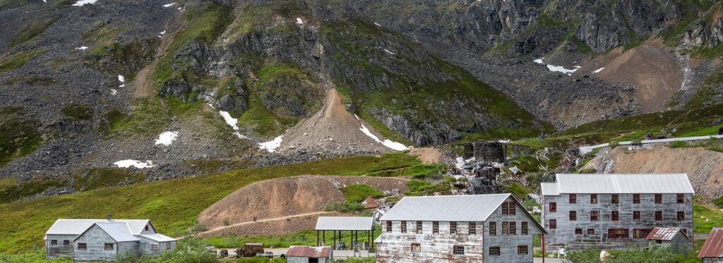A remote mountain village nestled among lush green hills with snow-capped peaks in the background in Mat-Su, Alaska