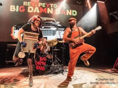 Rev. Peyton's Big Damn Band performs energetically on stage, with members dressed in vibrant outfits and playing unique instruments in Mat-Su, Alaska
