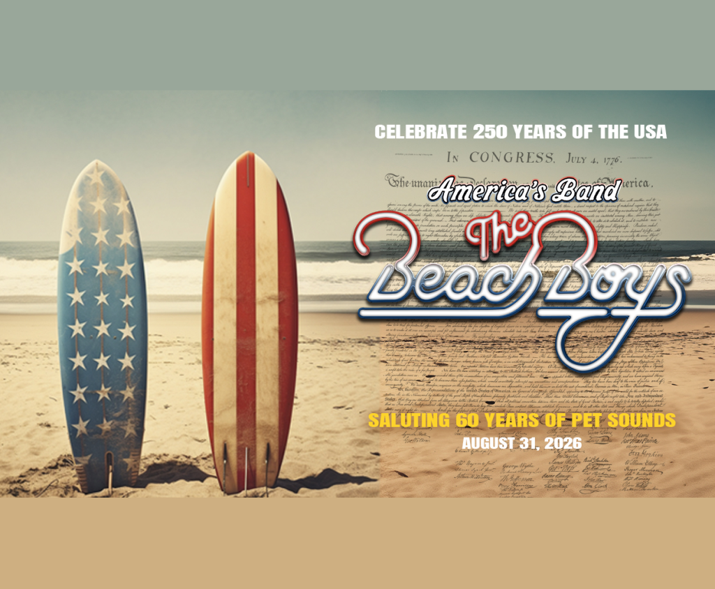 Two surfboards, one with an American flag design and the other with red and white stripes, stand upright in the sand on a beach with the ocean in the background. The text 'Celebrate 250 years of the USA' and 'America's Band: The Beach Boys' is superimposed on the image, along with details of a concert saluting 50 years of Pet Sounds on August 31, 2026 in Mat-Su, Alaska