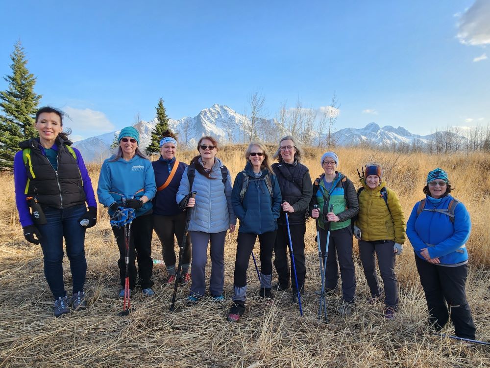A group of nine women standing in a field with mountains in the background in Mat-Su, Alaska