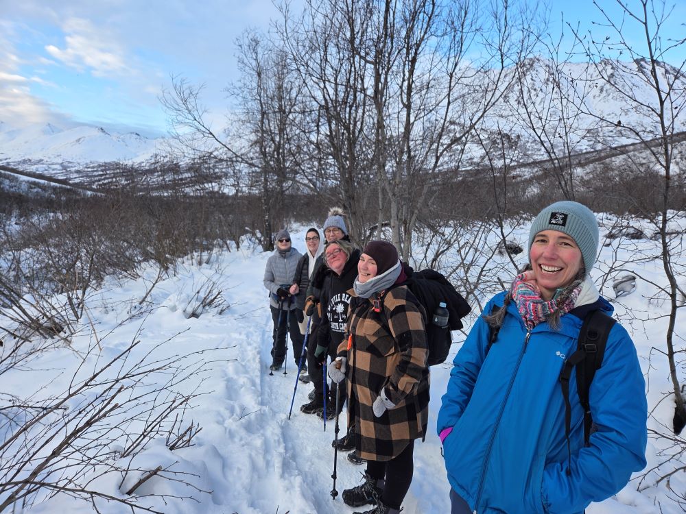 A group of friends hiking on a snowy trail in a winter landscape in Mat-Su, Alaska