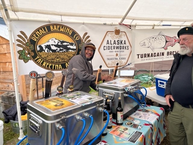 A man in a hoodie pours drinks at a brewery booth in Talkeetna, Alaska in Mat-Su, Alaska