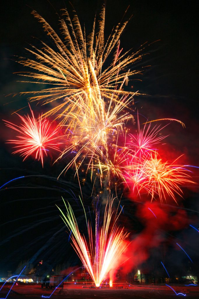 Colorful fireworks explode in the night sky above a dark landscape in Mat-Su, Alaska