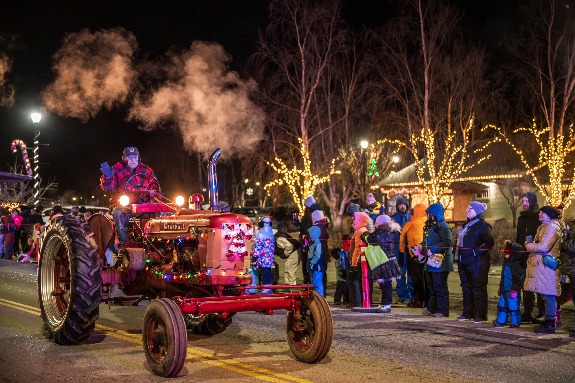 A man drives a vintage tractor decorated with lights in a nighttime holiday parade in Mat-Su, Alaska