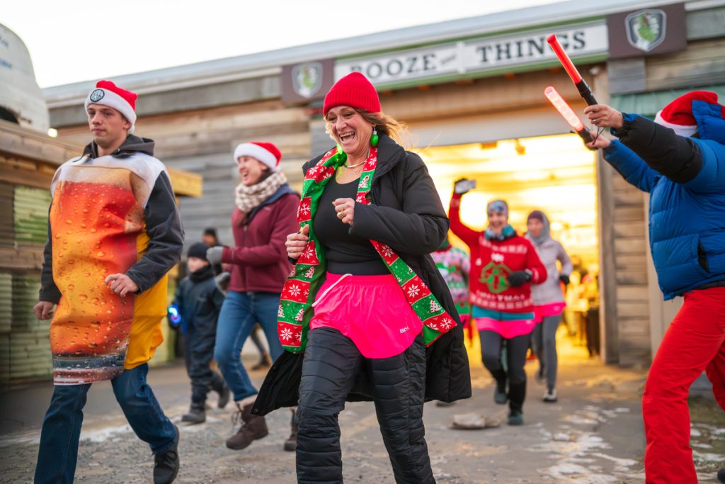 A group of people in festive holiday attire running outdoors during a fun event in Mat-Su, Alaska