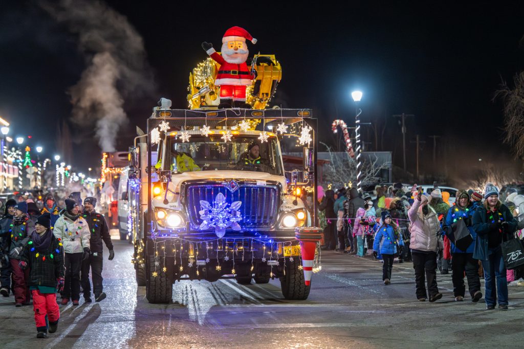 A decorated truck with a Santa figure on top drives through a night parade in Mat-Su, Alaska
